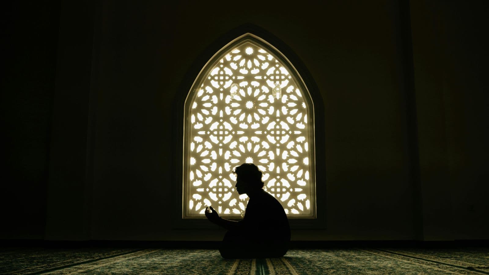 Silhouette non identifiable en recueillement dans une mosquée