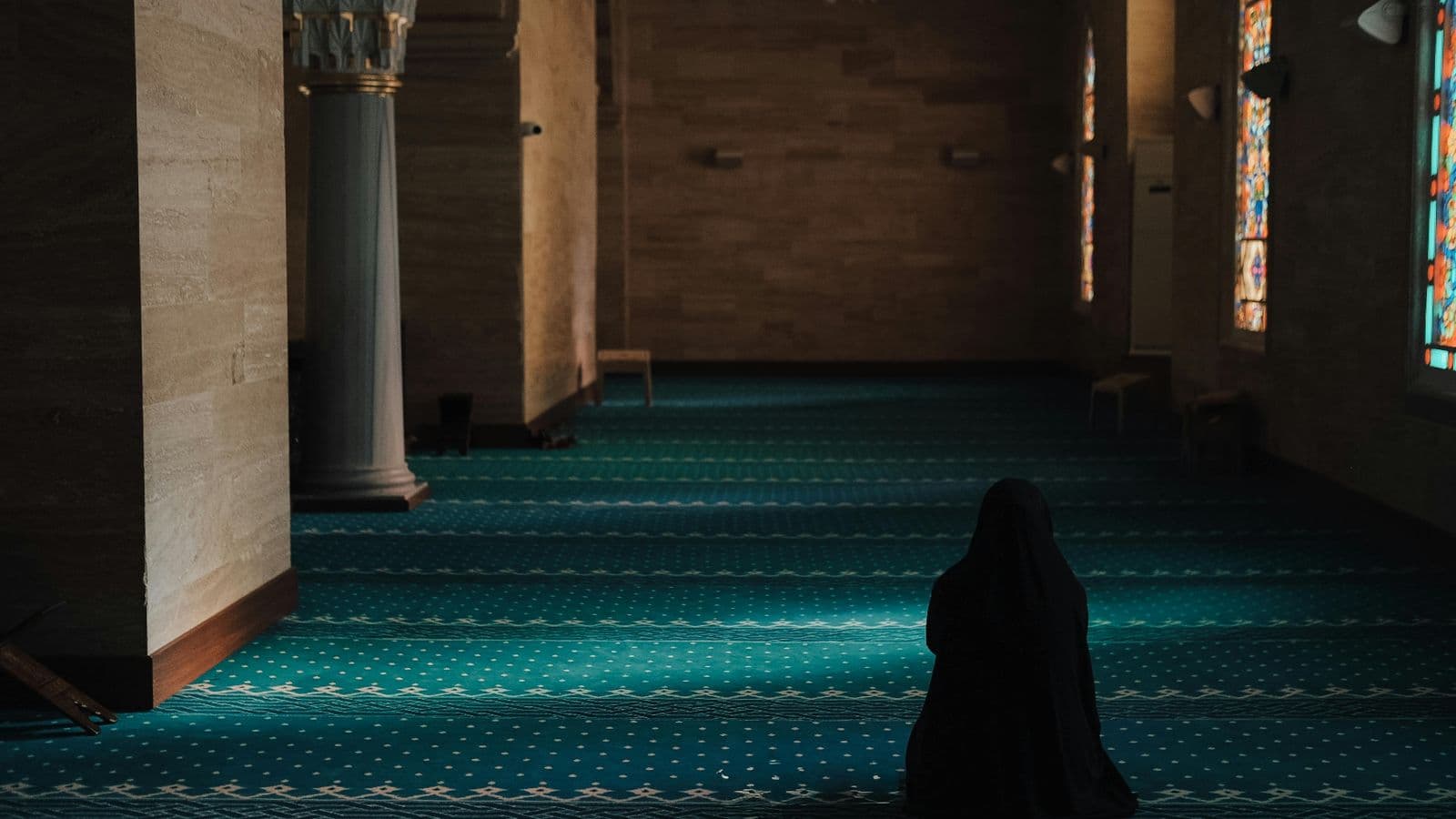 Femme vue de dos en recueillement dans une mosquée