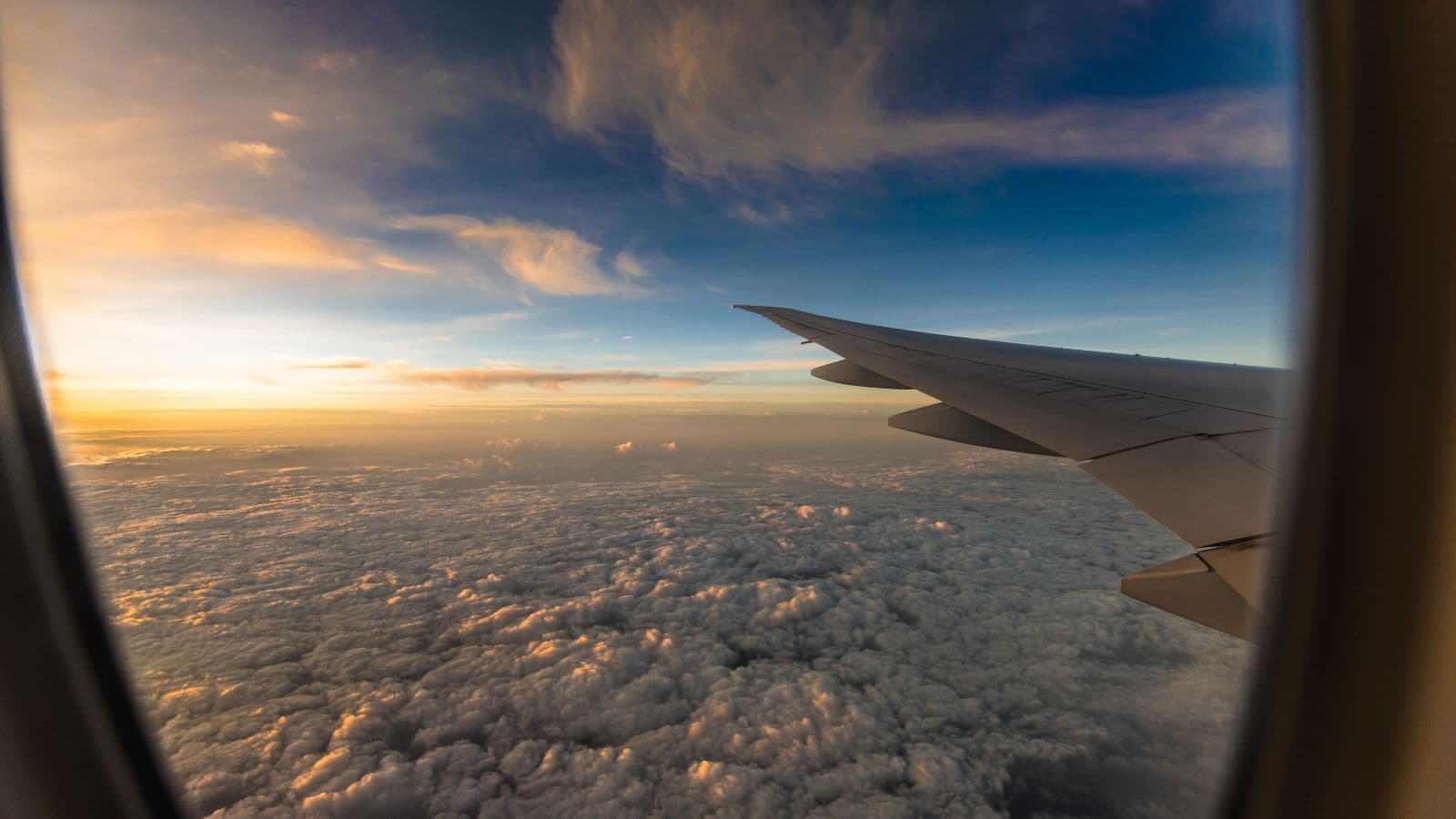 Aile d'avion au coucher du soleil au-dessus des nuages