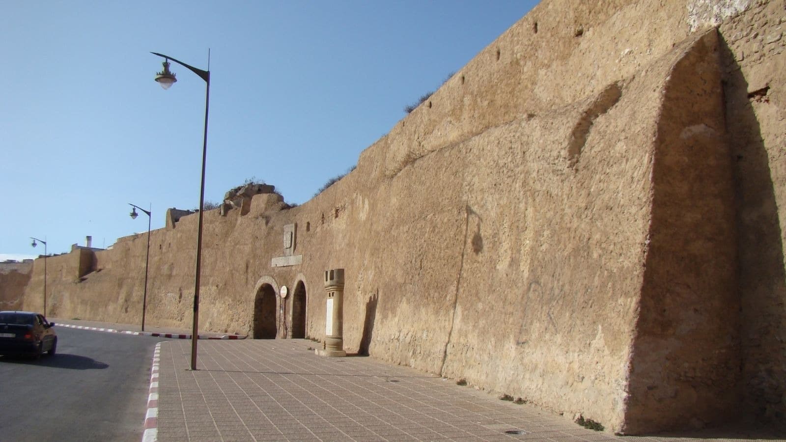 Long mur ancien percé d'une porte sombre