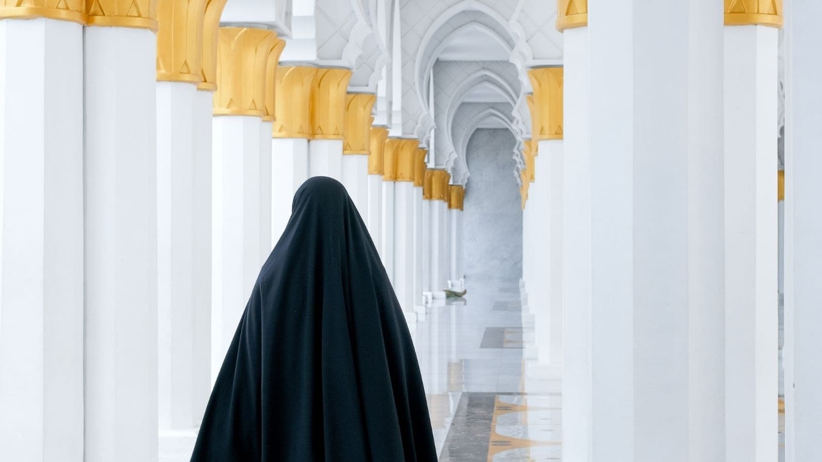 Femme voilée de dos dans une galerie blanche