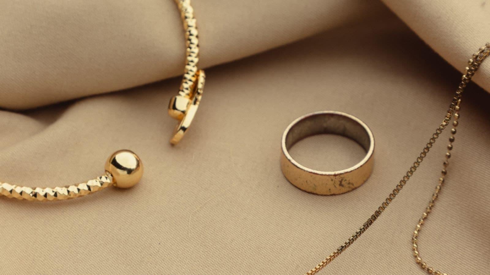 Bague et collier séparés sur un tissu beige