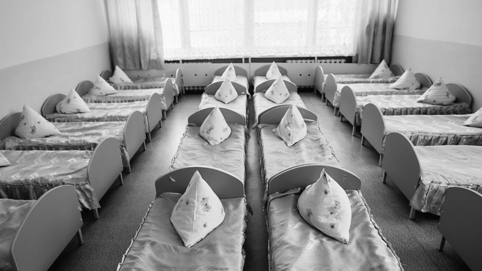 Dortoir collectif vide avec plusieurs lits alignés