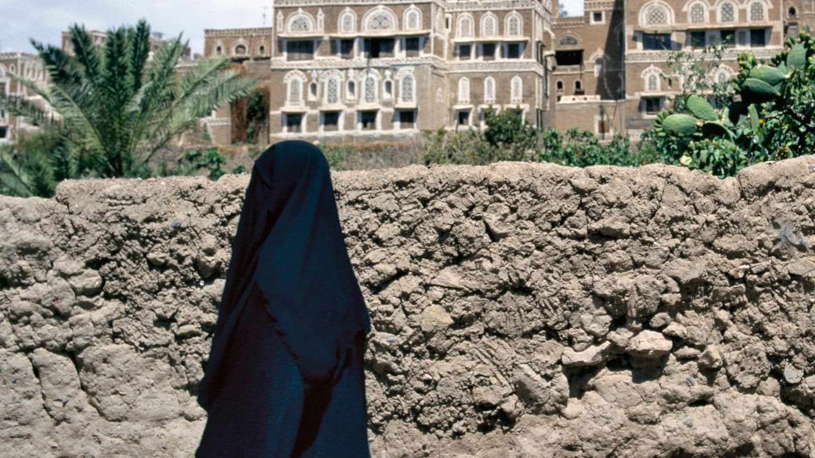 Femme voilée vue de dos devant une architecture traditionnelle