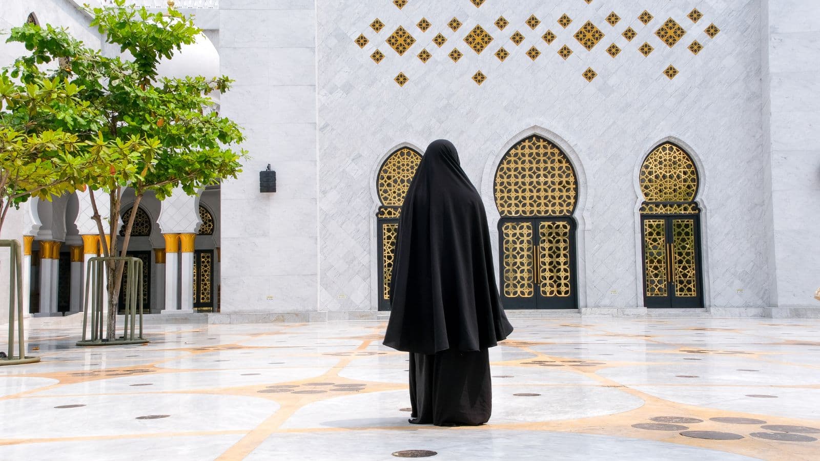 Femme voilée vue de dos dans la cour vide d'une mosquée