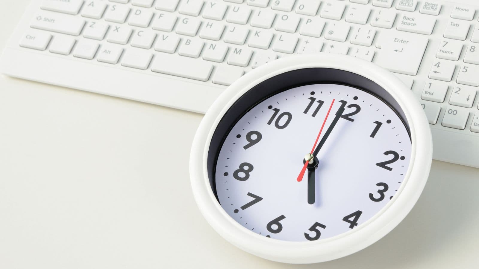 Horloge blanche posée devant un clavier d'ordinateur