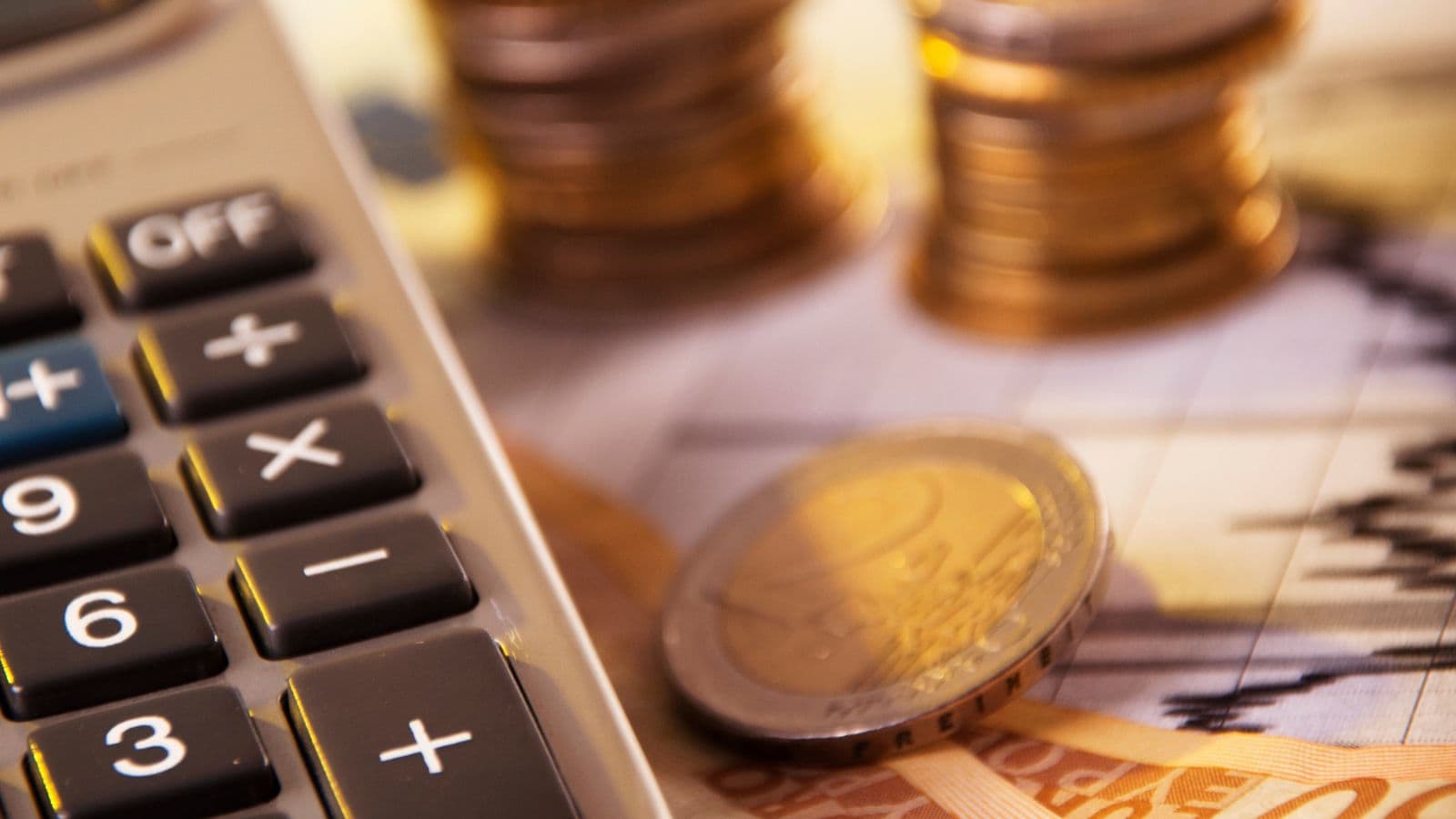 Calculatrice entourée de pièces et de billets