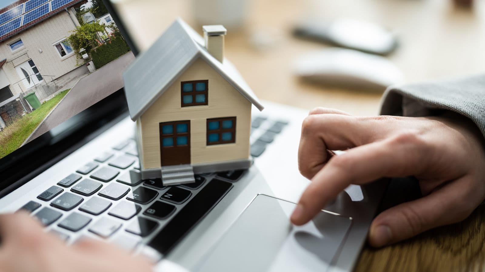 Maison miniature sur un ordinateur près d'une calculatrice