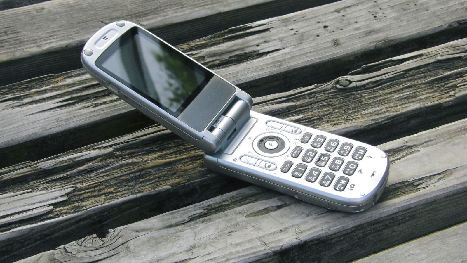 Téléphone portable à clapet posé sur des planches en bois