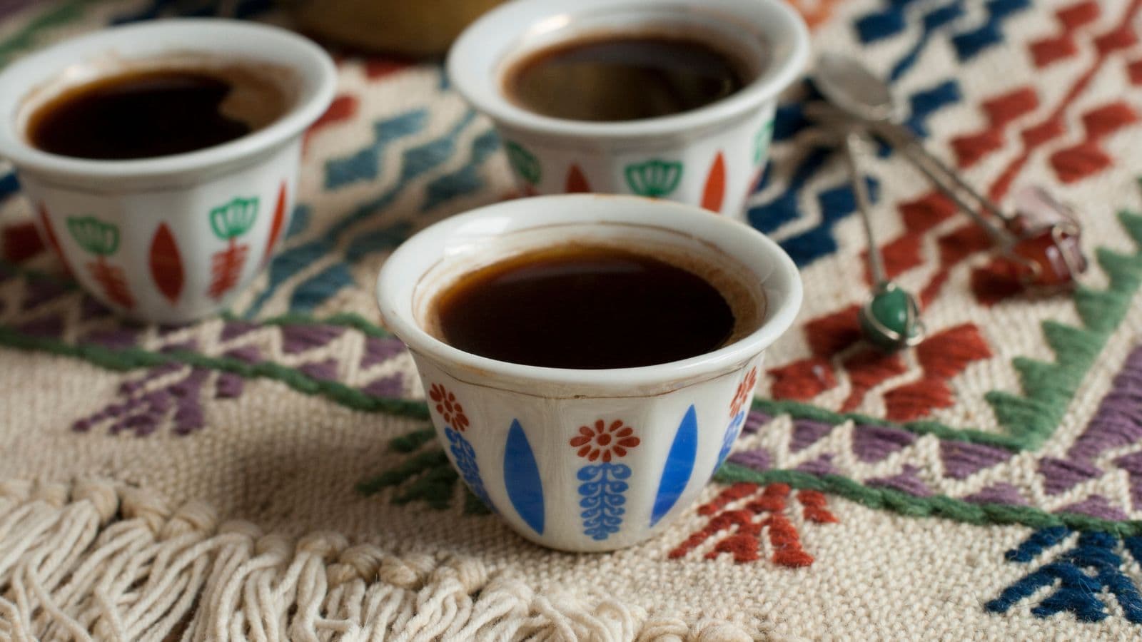 Trois petites tasses de café sur un textile traditionnel
