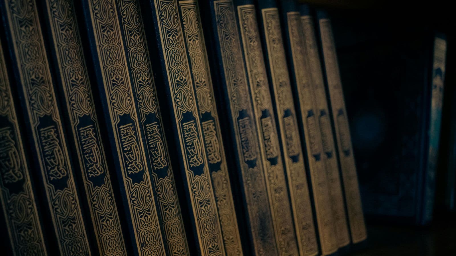 Volumes du Coran aux reliures sombres alignés sur une étagère