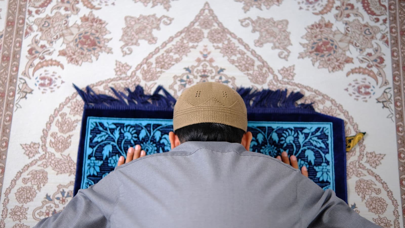 Personne en prosternation vue de dos sur un tapis de prière