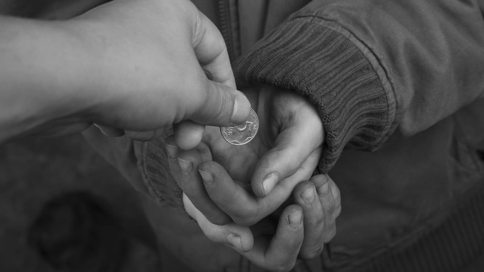Main donnant une pièce à une personne dans le besoin