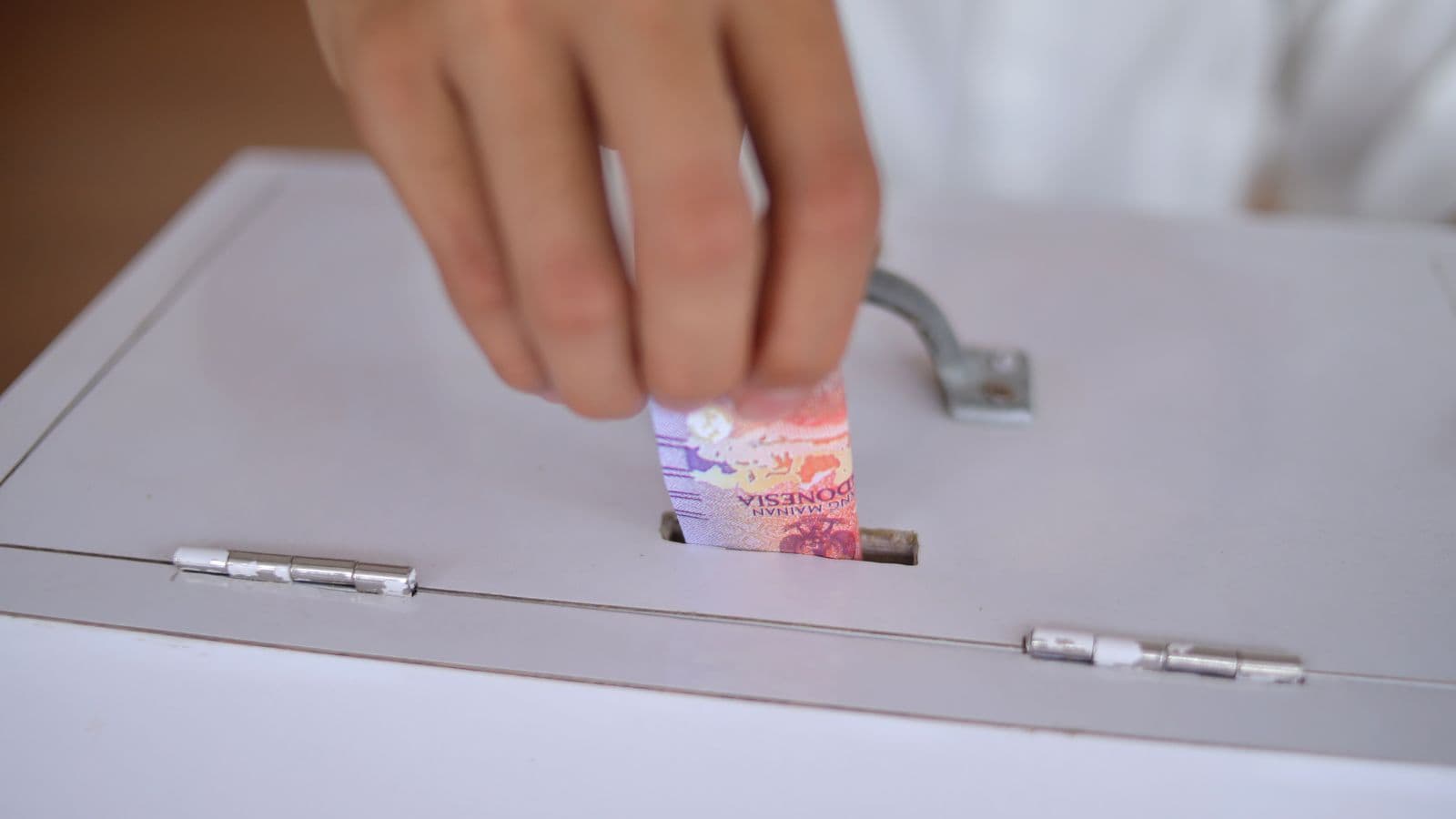 Main glissant un billet dans une boîte de collecte