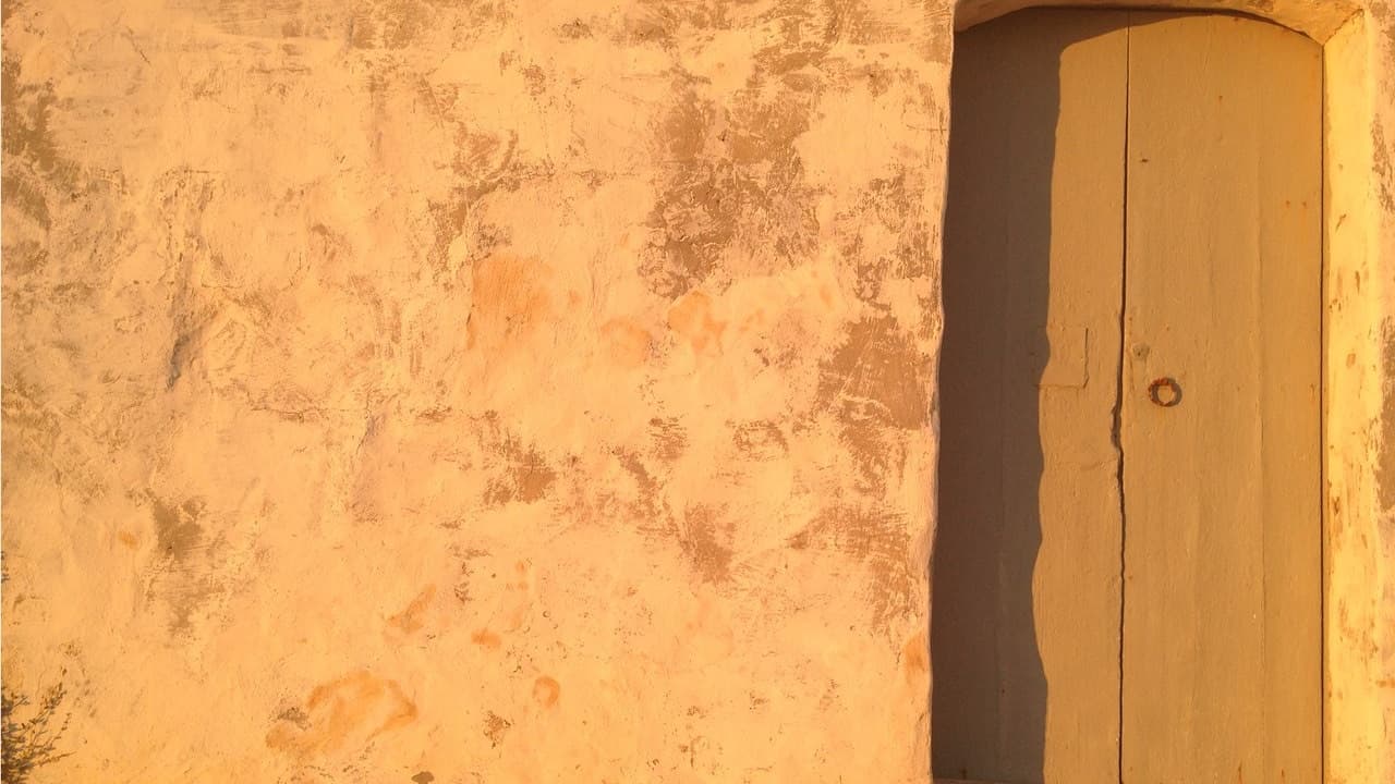 Porte ancienne dans un mur ocre éclairé par une lumière chaude