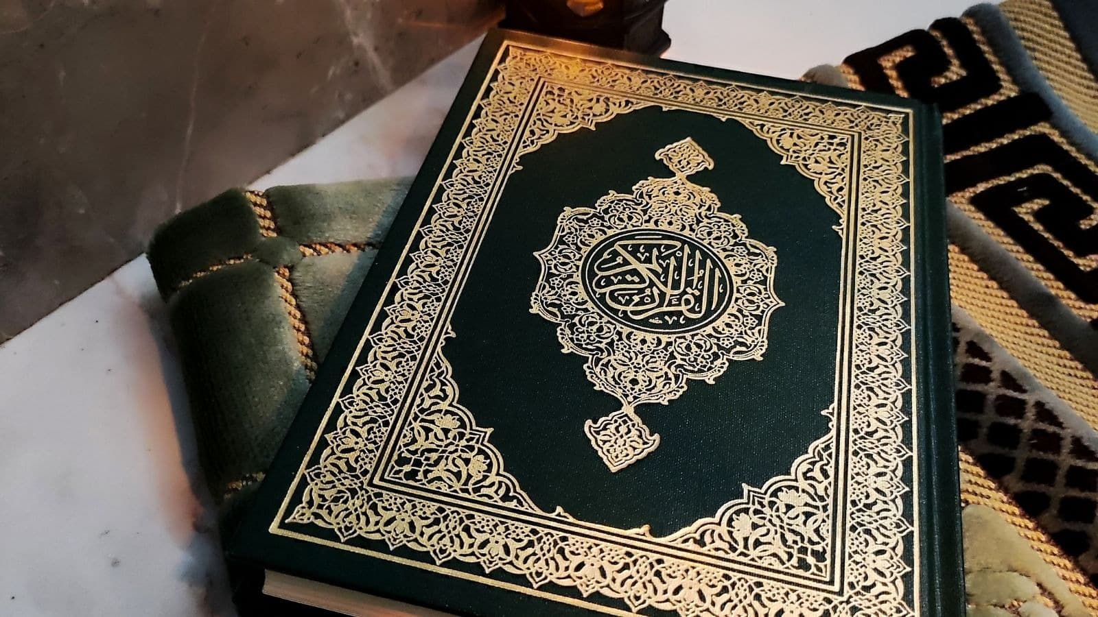 Coran fermé posé sur un tapis de prière sombre