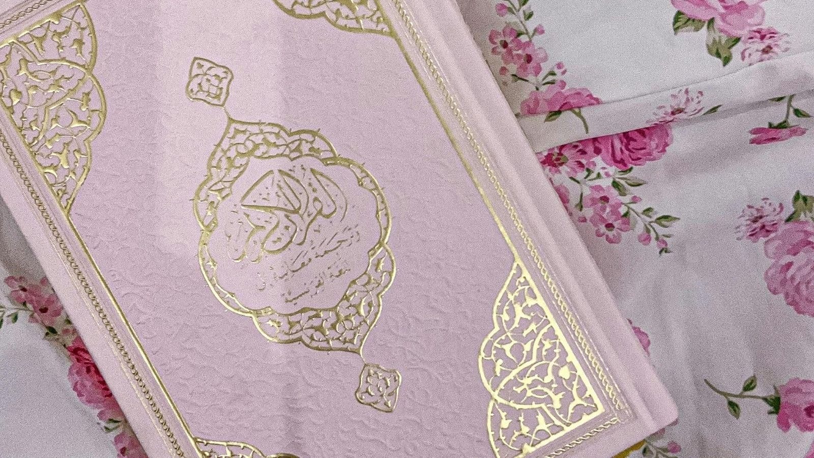 Coran à couverture rose entouré de fleurs