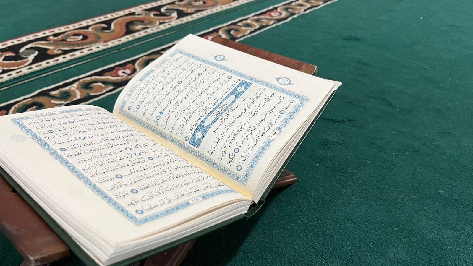 Coran ouvert posé sur la moquette verte d'une mosquée