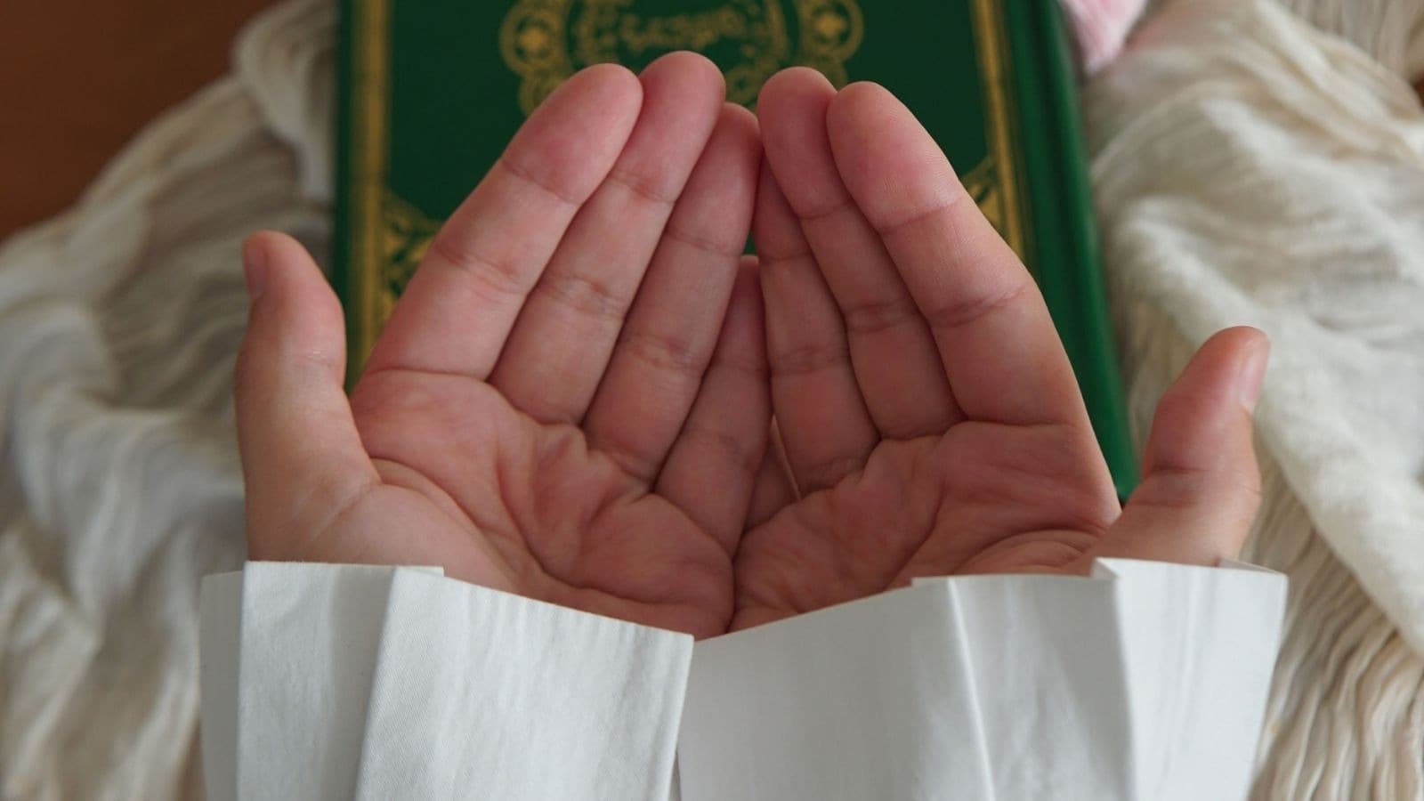 Mains ouvertes pour l'invocation devant un Coran