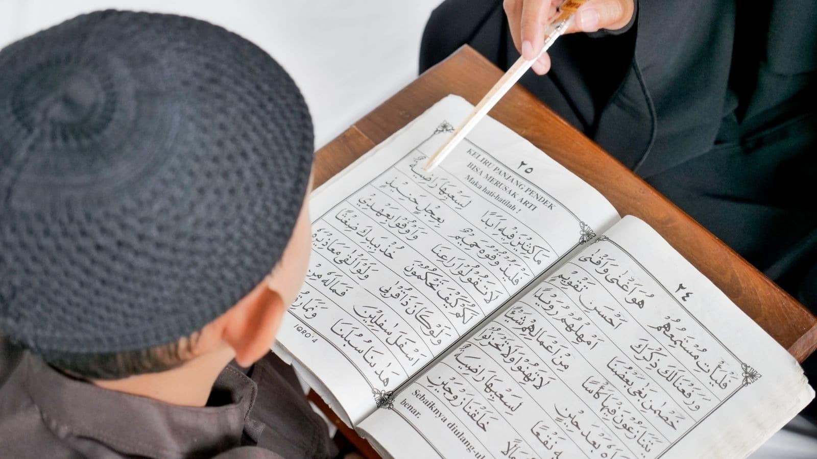 Enfant suivant les lignes d'un Coran avec une règle