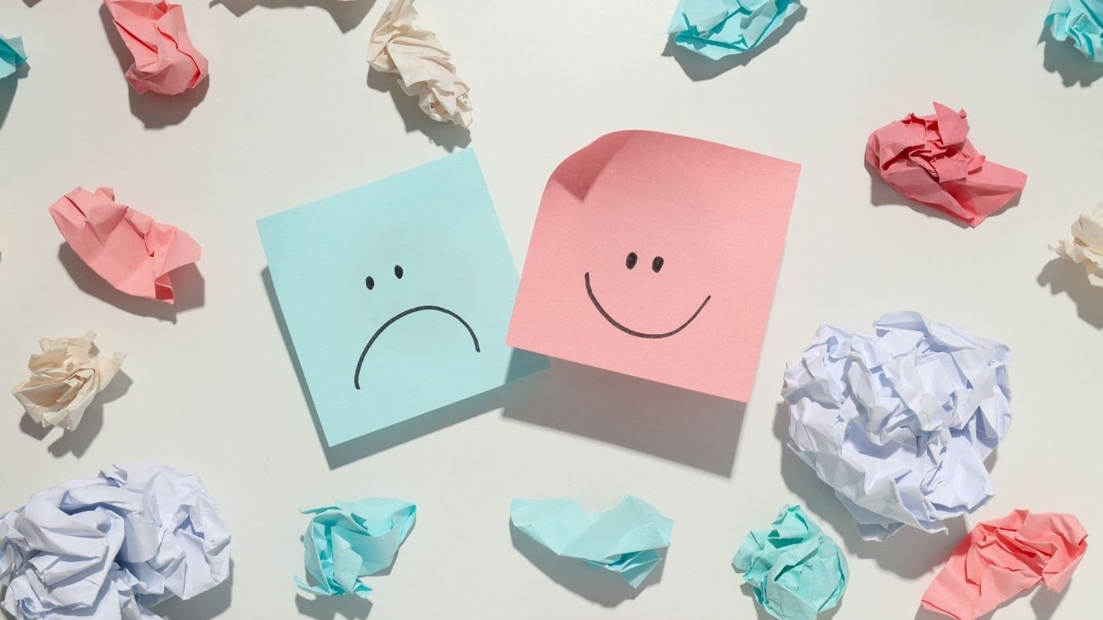 Notes souriantes et tristes entourées de papiers froissés