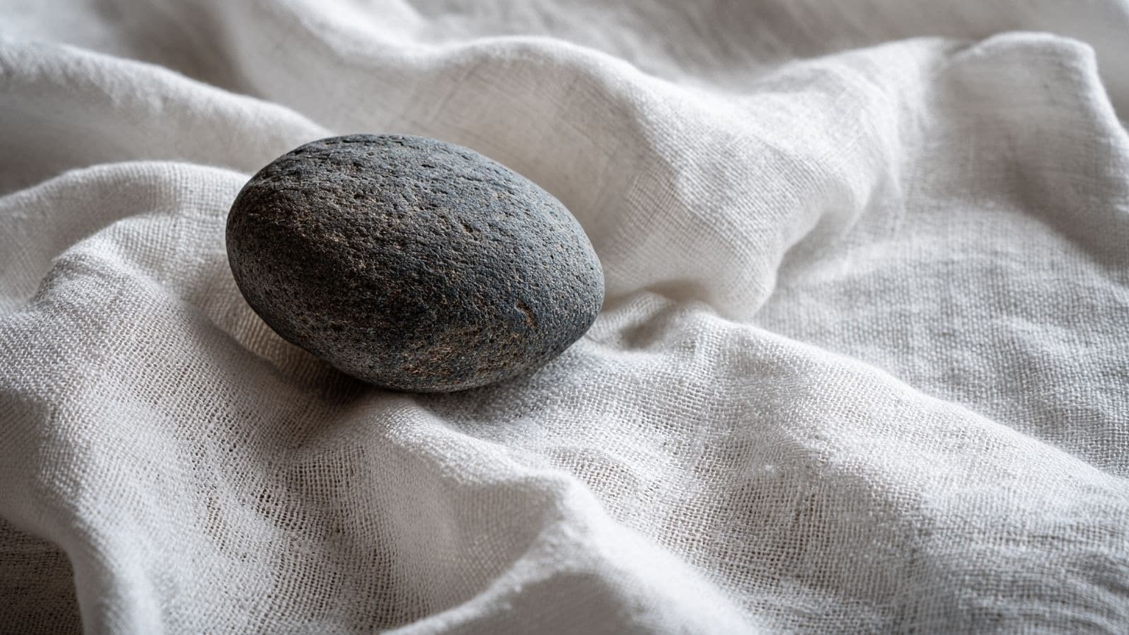 Galet sombre isolé sur un tissu blanc