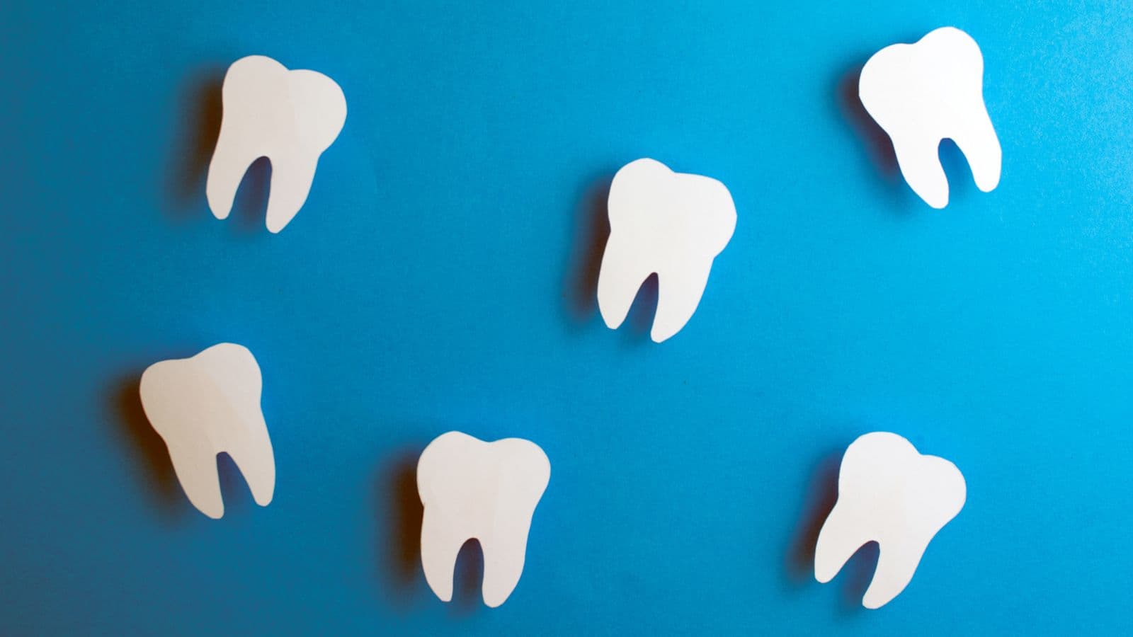 Formes de dents blanches disposées sur un fond bleu