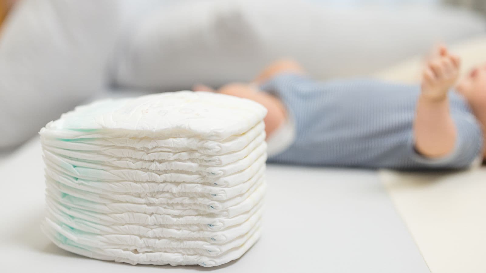Pile de couches pour bébé devant un nourrisson flouté