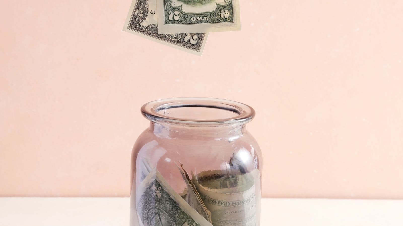 Bocal contenant des billets sur un fond rose